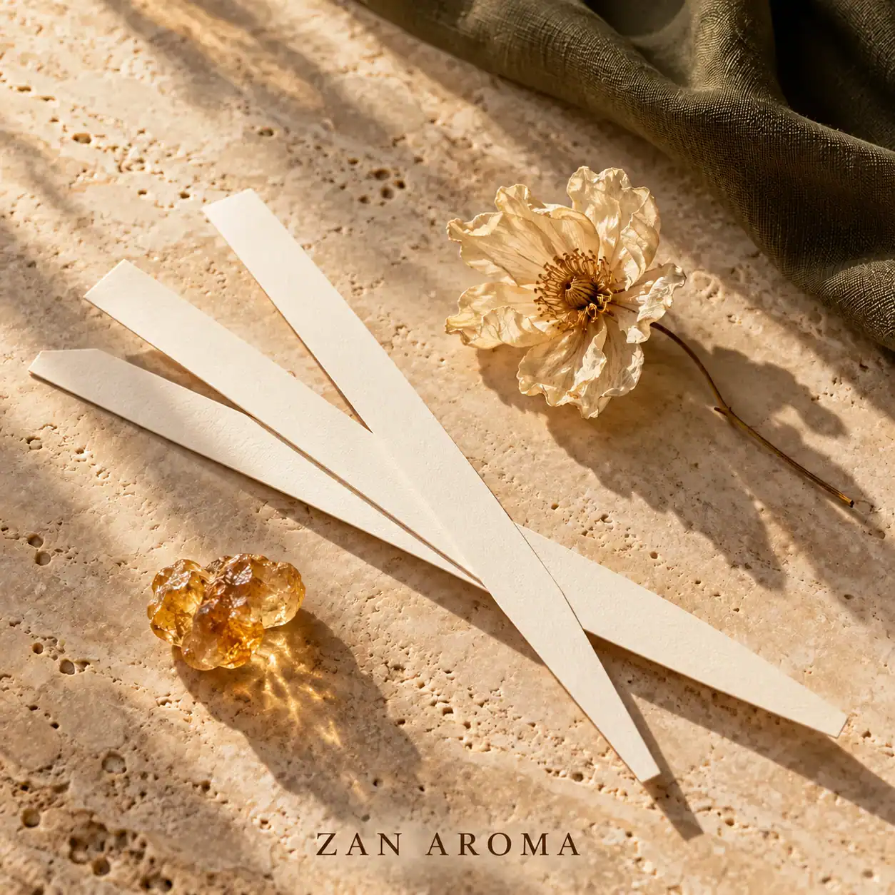 Composition éditoriale de mouillettes, d’une fleur séchée et de résine dorée sur une pierre claire